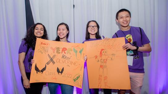 Orientation leaders show off the superhero-themed posters they created for their orientation groups
