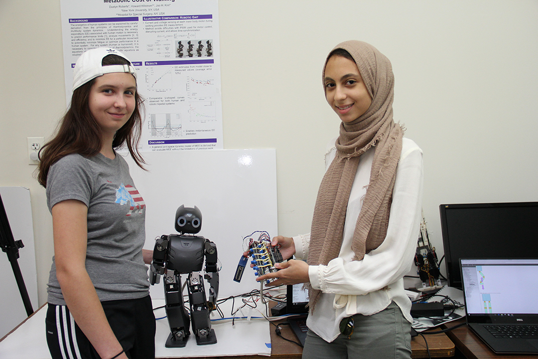 two students holding up a robot