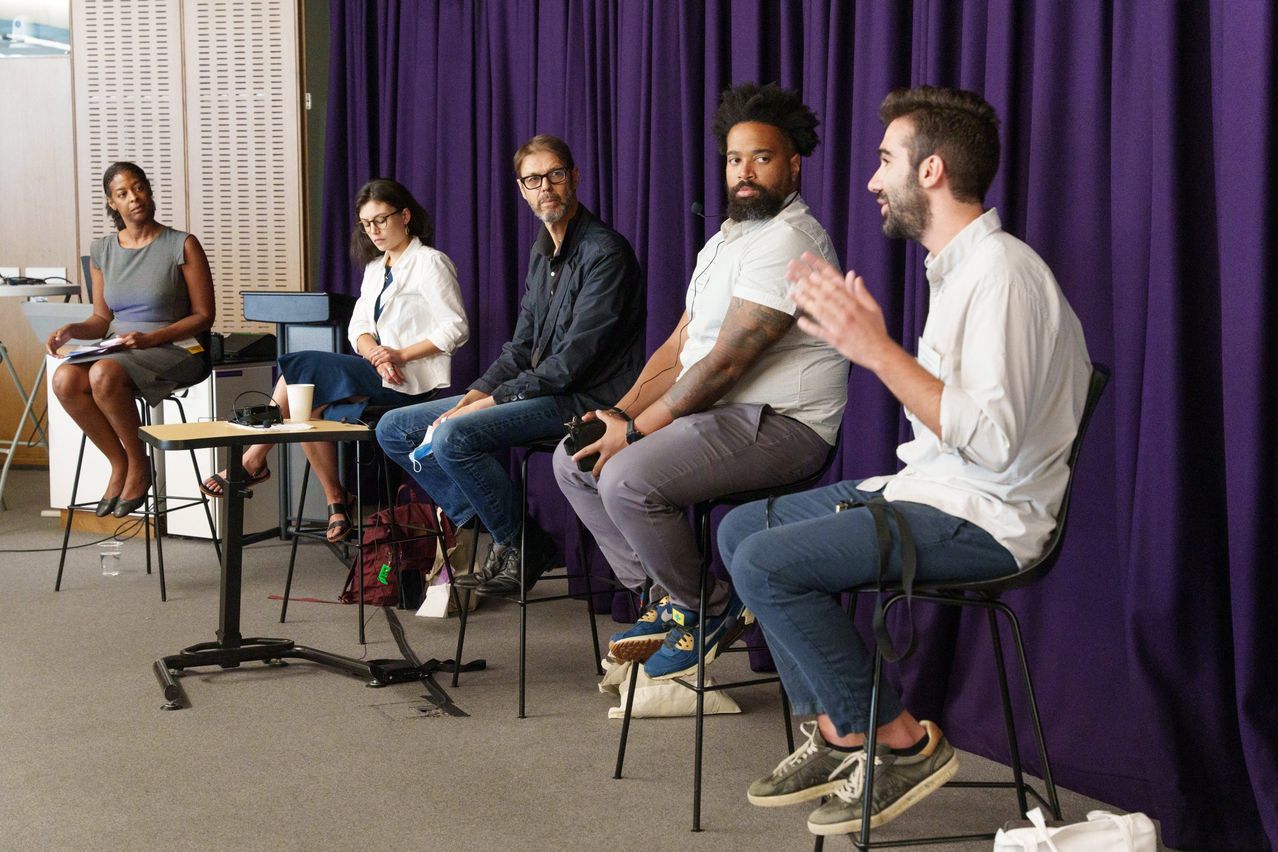 PhD students and faculty seated on stools on a discussion panel