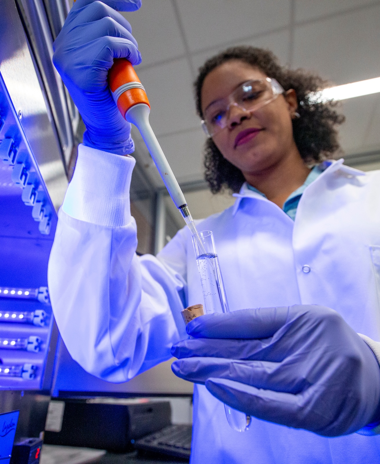 student in lab coat holding pipette