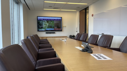Conference room with a long table, five chairs on each side, and a display at the end of the table.