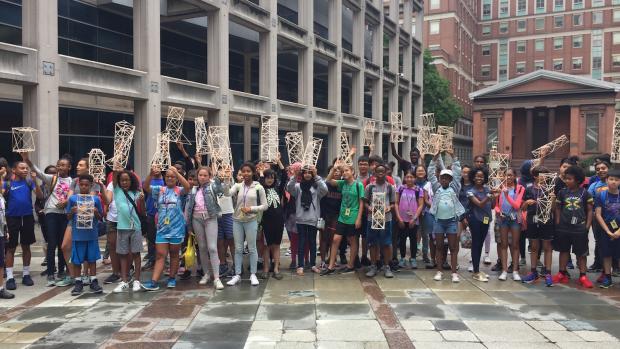 Summer of STEM students pose with their projects outside of NYU Tandon's Pfizer Auditorium. 