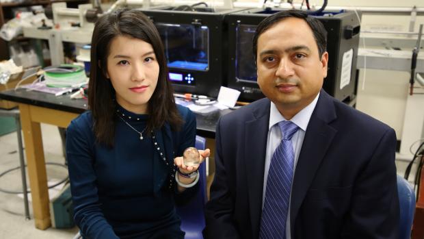 Fei Chen holding a 3D printed item next to Professor Gupta