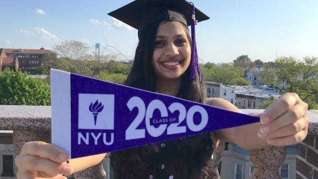 student wearing grad cap holding NYU 2020 flag