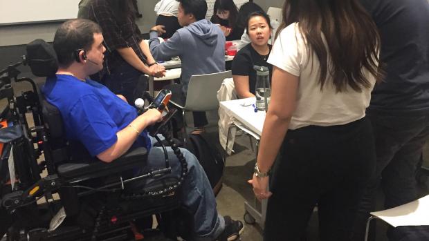 man in wheelchair interacting with students