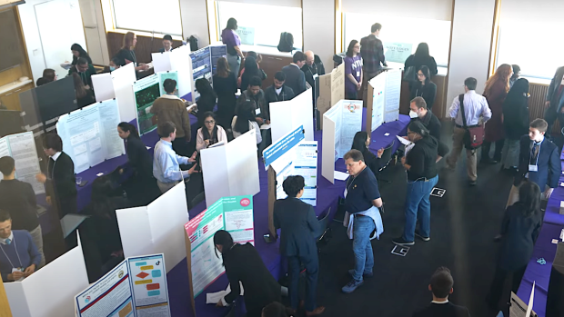 overhead view of room full of research posters, high school students, and onlookers