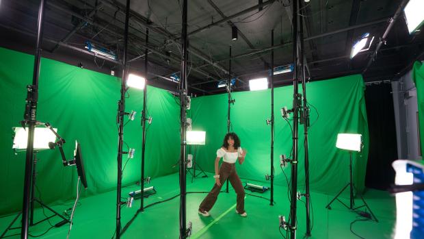 Person standing in front of a green screen and camera set up in brooklyn navy yard