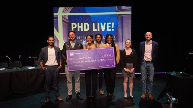 Awardees of the Ph.D Live competition on stage holding an oversized cheque