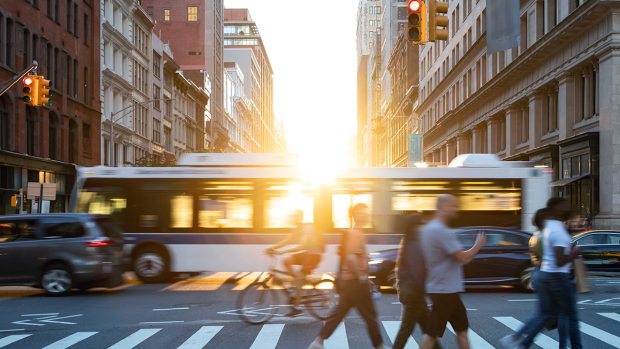 An image of the streets of New York City with busses, cars, bicyclists and pedestrians.