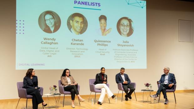 a panel seated on stage with slide of headshots behind them