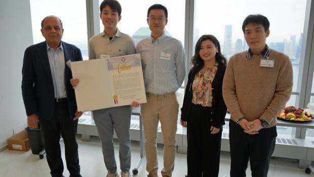 A group of five people stand, holding a large paper titled "Citation"