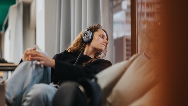 Woman looking out window while wearing headphones