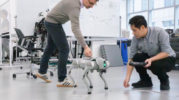 Professor and grad student working with robotic dog