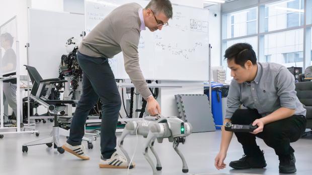 Professor and grad student working with robotic dog