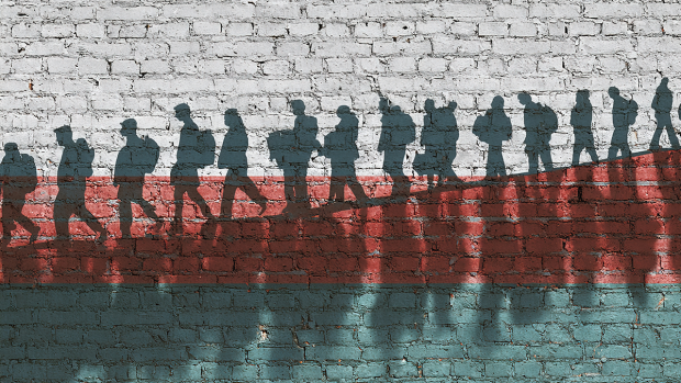 Illustration of a line of silhouettes of migrants walking in a line.