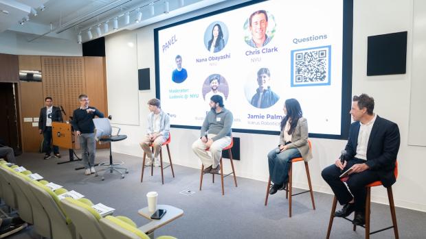 a panel of speakers seated in front of a large screen displaying their photos