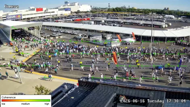 a crowd of pedestrians walking near a stadium with arrows indicating movement