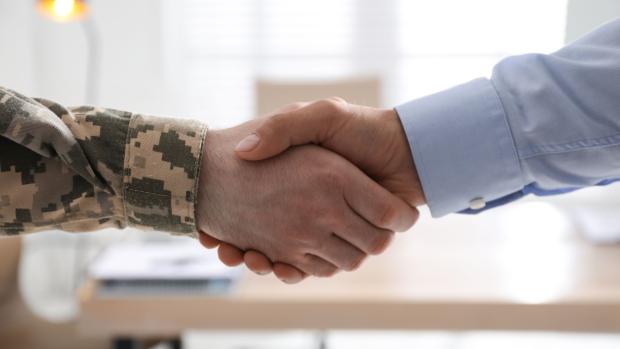 A Veteran shaking hands with a business man.