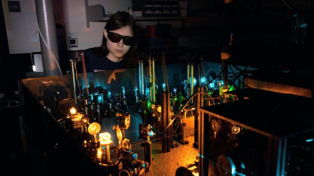 Amelia Klein wearing goggles behind a machine in a dark room.