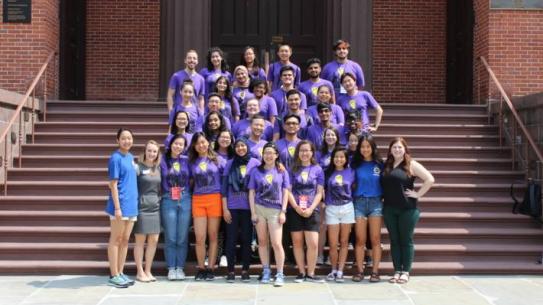  group of students wearing orientation shirts on steps of Wunsch Building