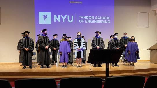 The dean and other faculty in academic robes on stage