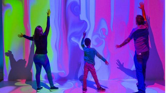 three people interacting in a color/media exhibit 
