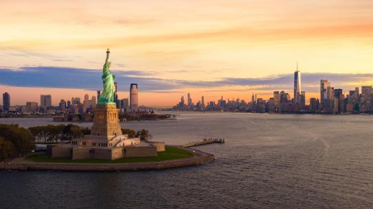 statue of liberty with sunset skyline 