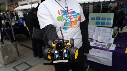 roving robot held by student wearing research exhibit t-shirt