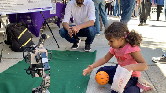 a young girl plays ball with a small robot