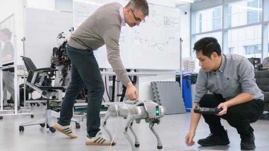 Professor and grad student working with robotic dog