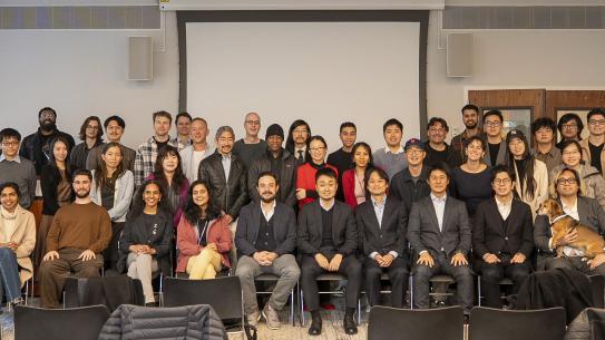 A large group of people stand together, posed in rows smiling