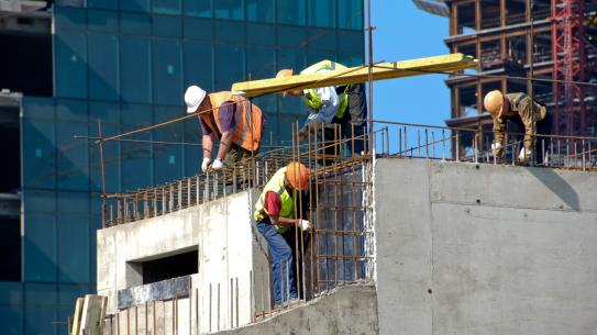 Construction Workers laying down the foundation of a building.