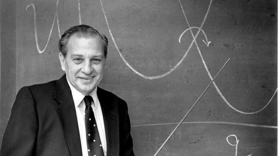 Rudolph Marcus standing in front of a chalkboard