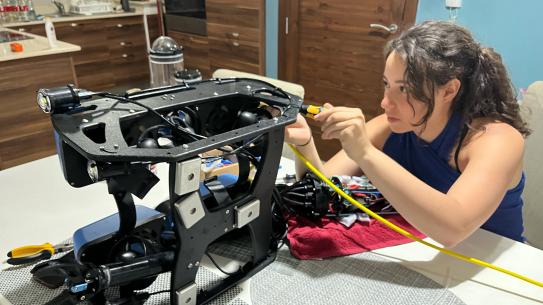 Young woman working on an underwater drone set on a desk.