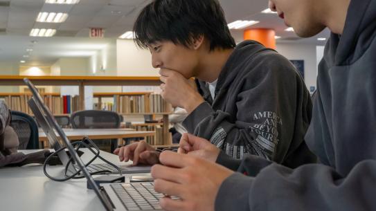 students working on laptop in the library