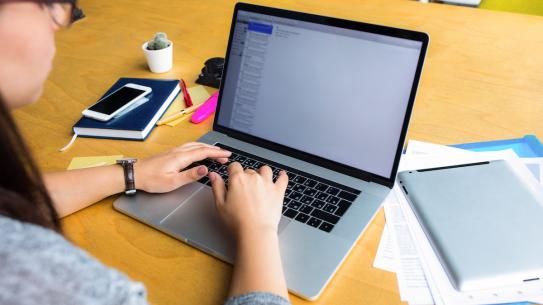 student typing on laptop