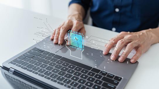 hands typing on laptop with "AI" superimposed 