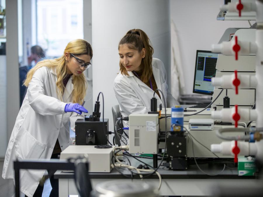 two female students in lab coats working in lab