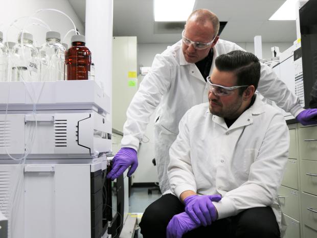 Grad student in lab coat with professor  in the lab