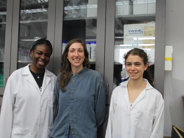 Professor Andrea Silverman flanked by two female students in the lab