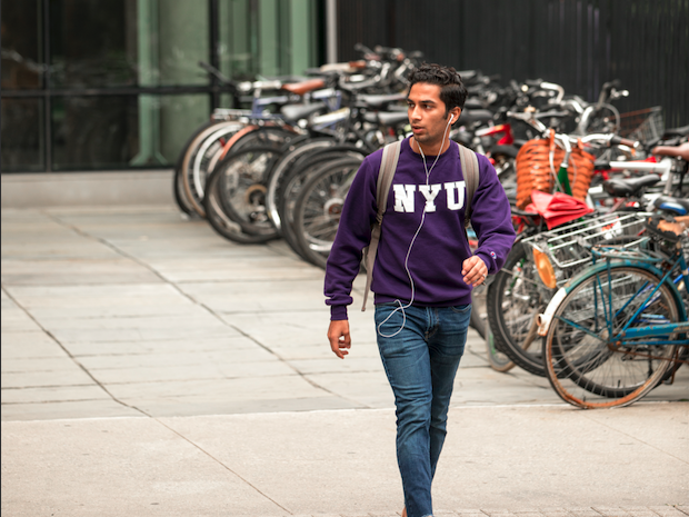 Student wearing NYU sweatshirt walking in NYC