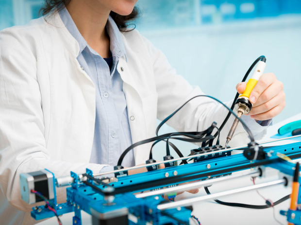 female student in lab coat working with microcontroller and robot cnc module