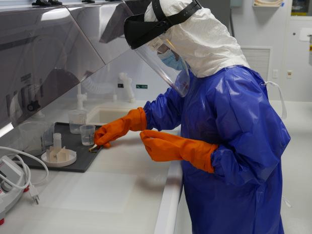 person dressed in cleanroom garb conducting research