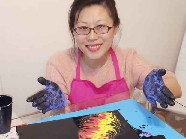 a smiling woman working on an art project