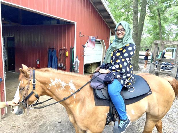a young woman wearing a headscarf riding a horse