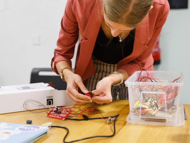 a student bent over working on electrical circuit