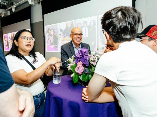 The dean smiling while at a round table with students
