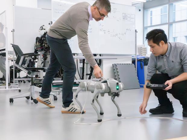Professor and grad student working with robotic dog