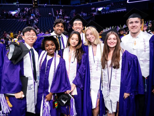 diverse group of smiling students in graduation robes at commencement ceremony