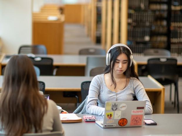 a student wearing headphones studying in the Dibner Library
